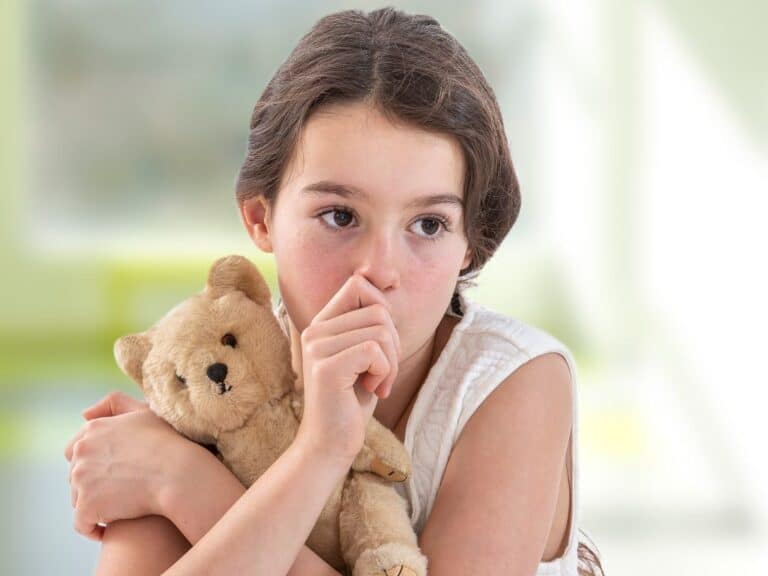 A young child sleeping in bed sucking their thumb for comfort.