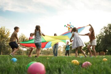 A group of kids playing together in the grass at the playground. Everyone is actively engaged in a fun game.