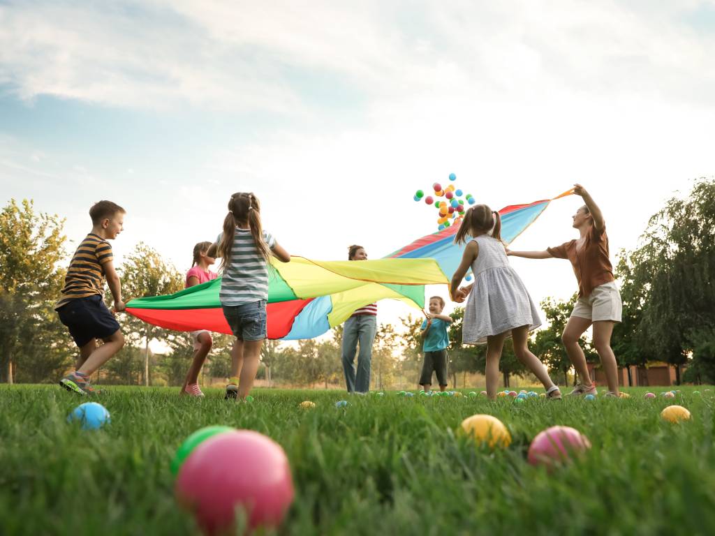 A group of kids playing together in the grass at the playground. Everyone is actively engaged in a fun game.