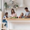 A happy family of four at the kitchen island enjoying a meal together. There is one kid sitting next to each parent.