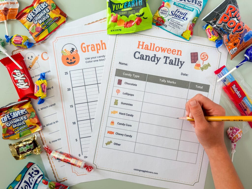 Printable Halloween candy math worksheets surrounded by assorted trick-or-treat candy.