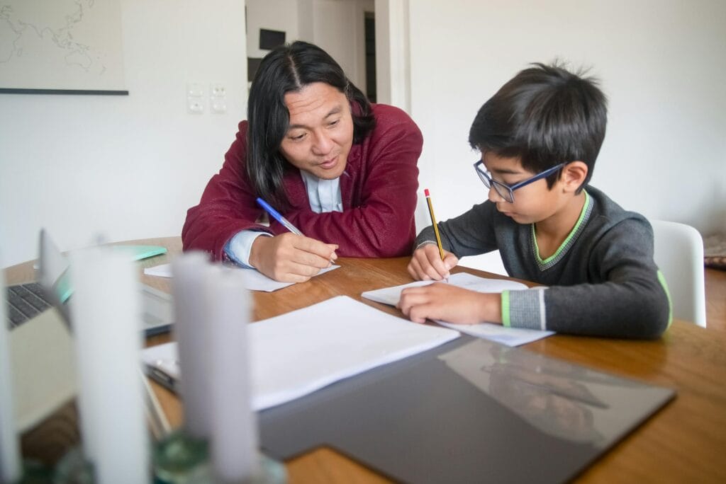 An adult tutoring a child at home, focusing on learning and education.