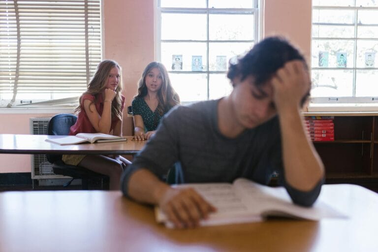 Focused on a teenager feeling bullied in a classroom environment with peers.