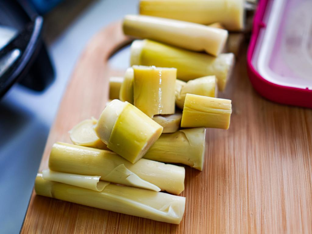 A pile of peeled bamboo shoots arranged together with cut ends and layered surfaces visible on each piece.