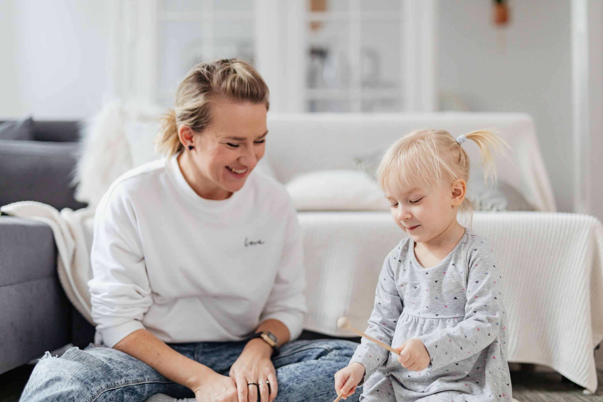 A joyful mother and daughter duo playing xylophone together in a cozy living room.