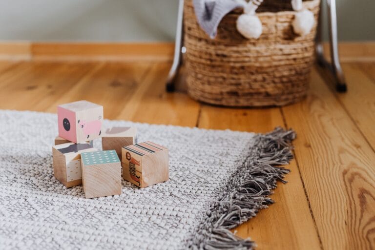 Colorful wooden blocks on woven rug in a cozy indoor playroom setting.