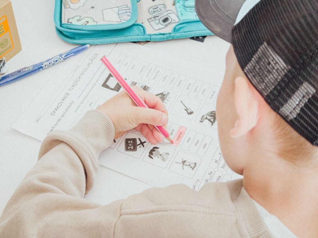 A young boy works on a homework sheet at home, focusing intently on his assignments.