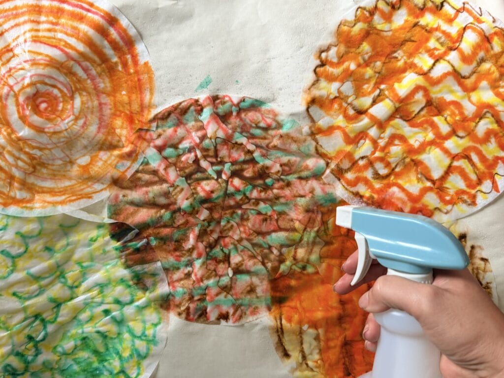 Spraying colored coffee filers with water