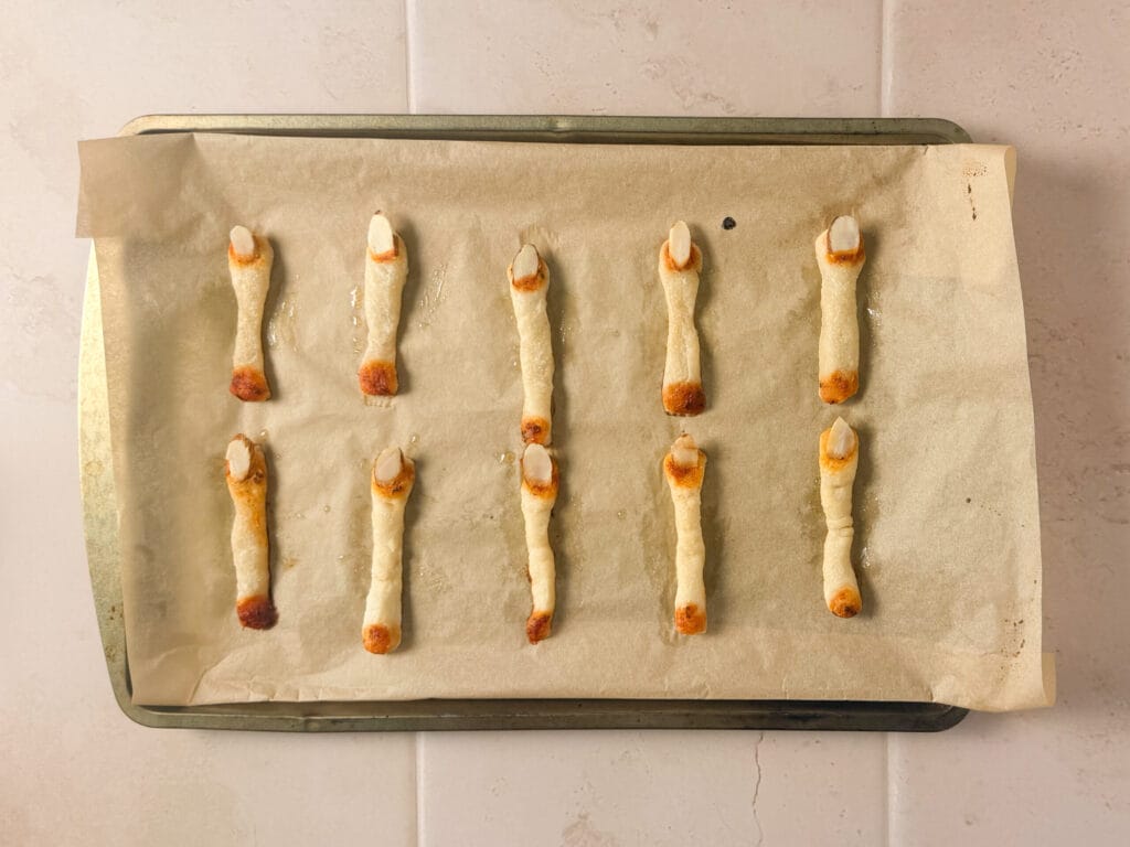 Baked Halloween finger breadsticks with almond fingernails and bloody marinara sauce.