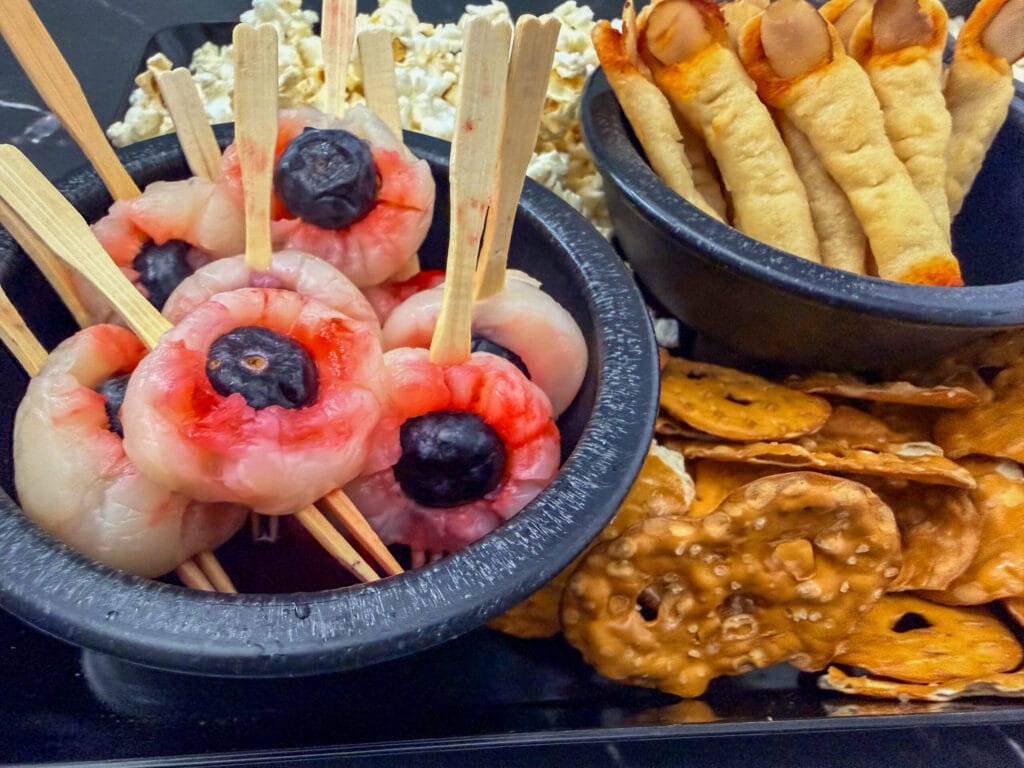 Close-up of bloody lychee eyeballs with blueberries and creepy almond fingernail breadsticks.